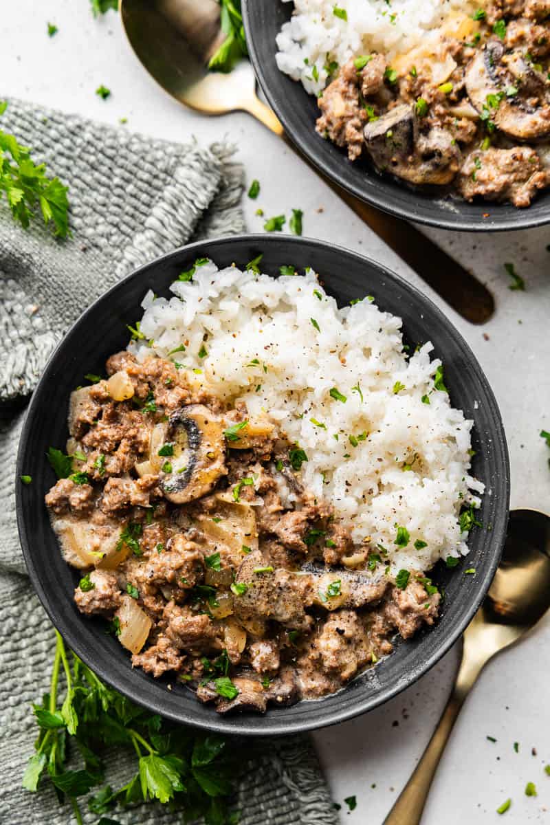 An overhead view of a bowl of ground beef stroganoff served over white rice.