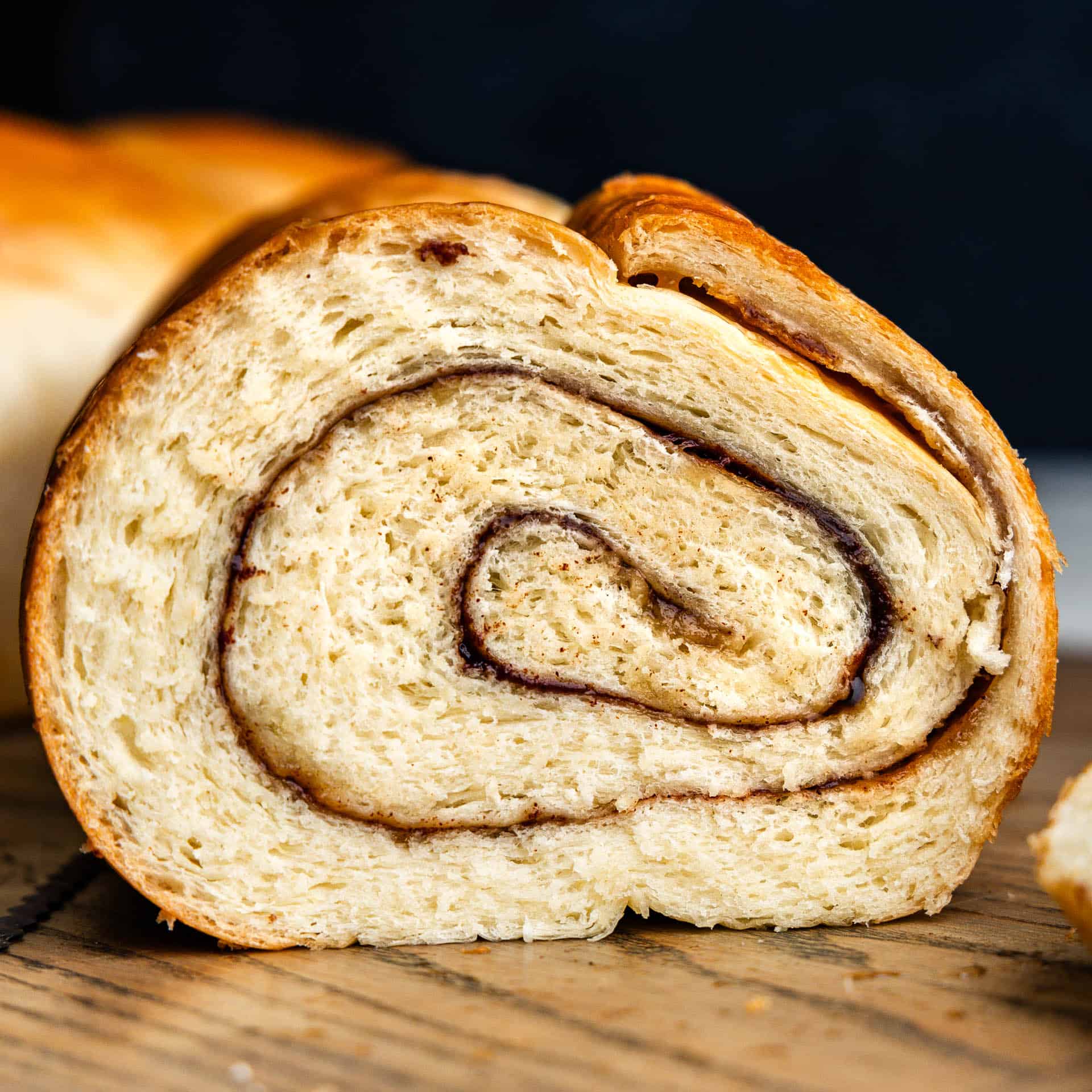 side view of a slice of cinnamon swirl bread on cutting board