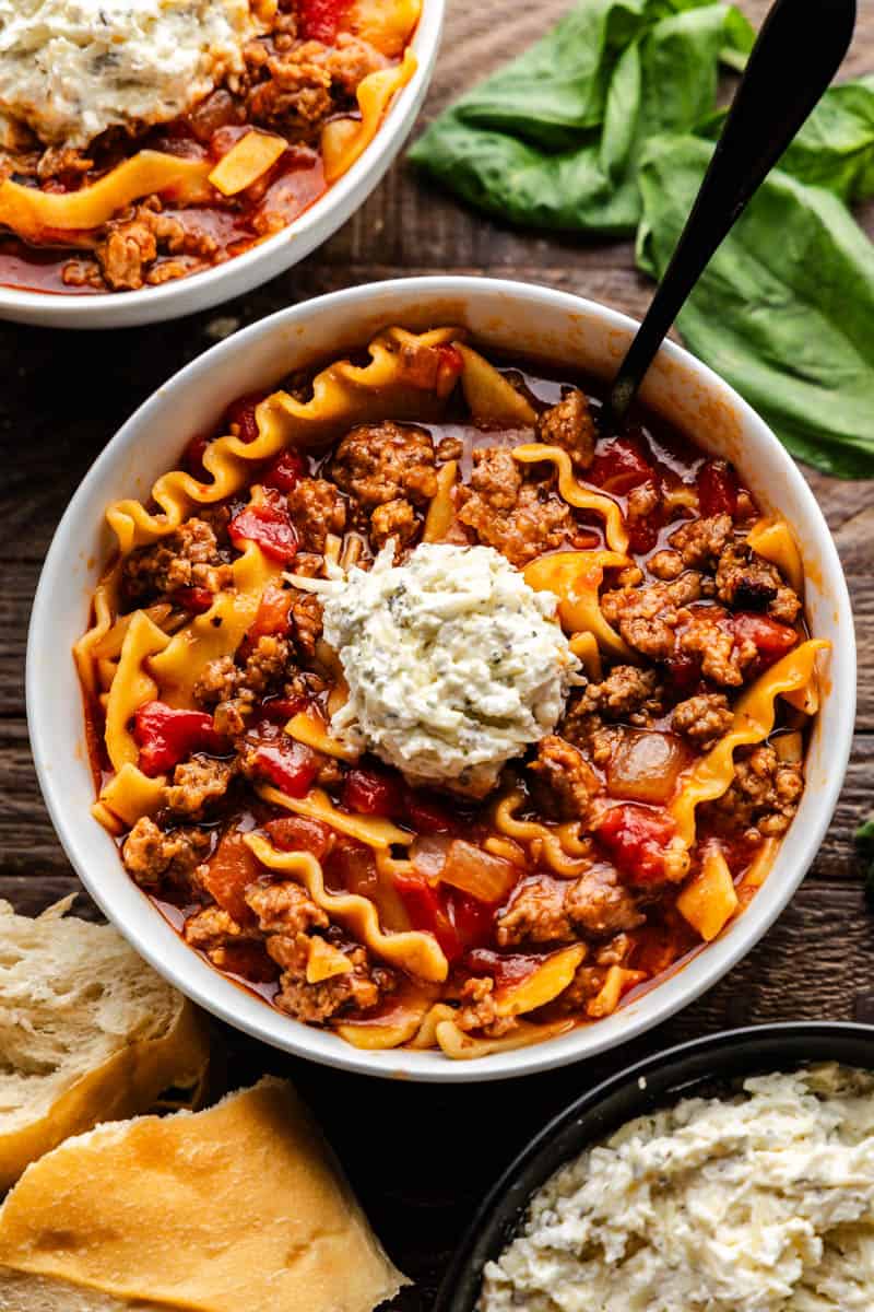 An overhead view of a bowl of lasagna soup with a dollop of ricotta cheese on top.