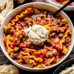 A close up view of a bowl of lasagna soup with a dollop of seasoned ricotta cheese on top.