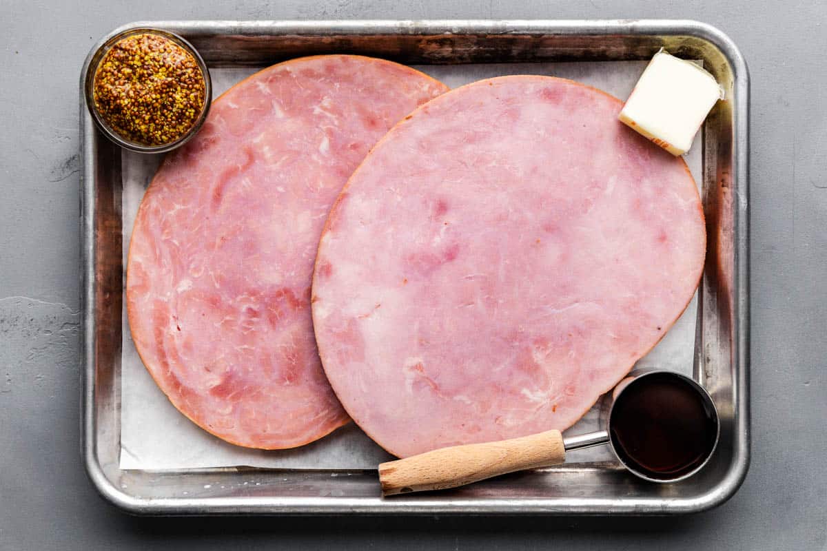 raw ingredients needed to make maple and mustard glazed ham steak on baking sheet