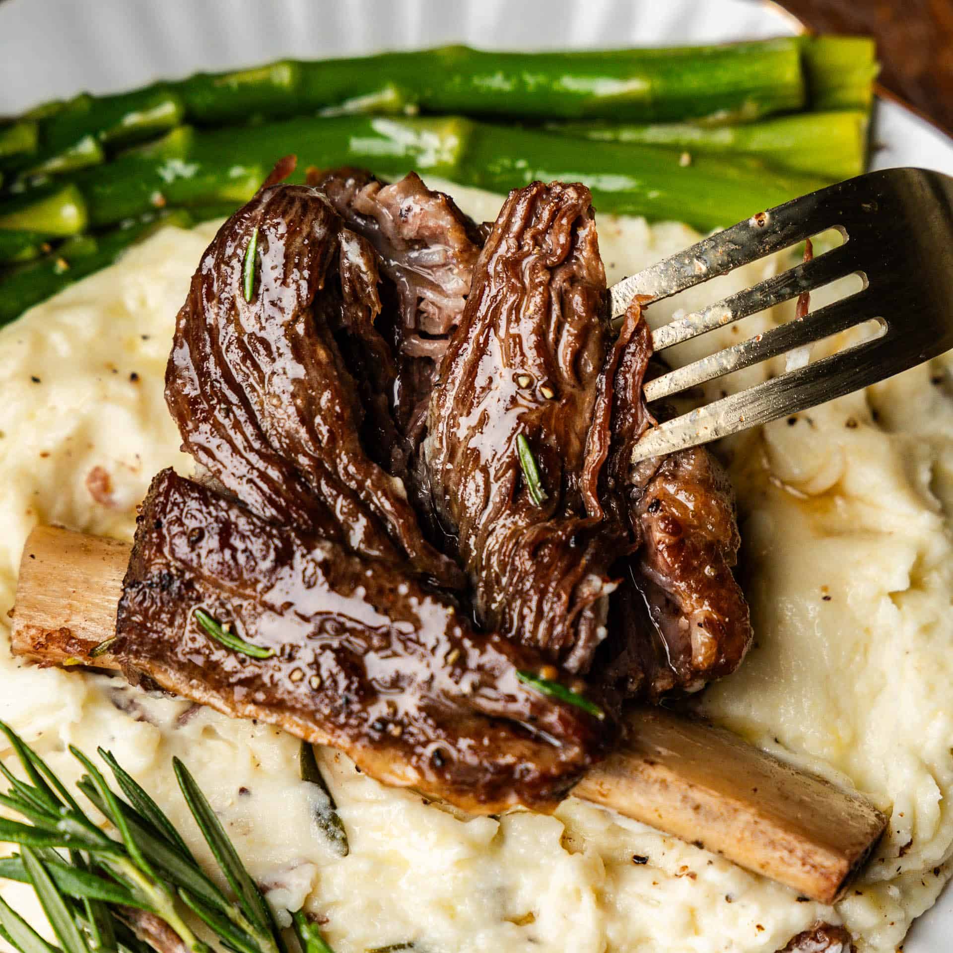 Fork with a heaping of slow cooker beef ribs served over mashed potatoes.