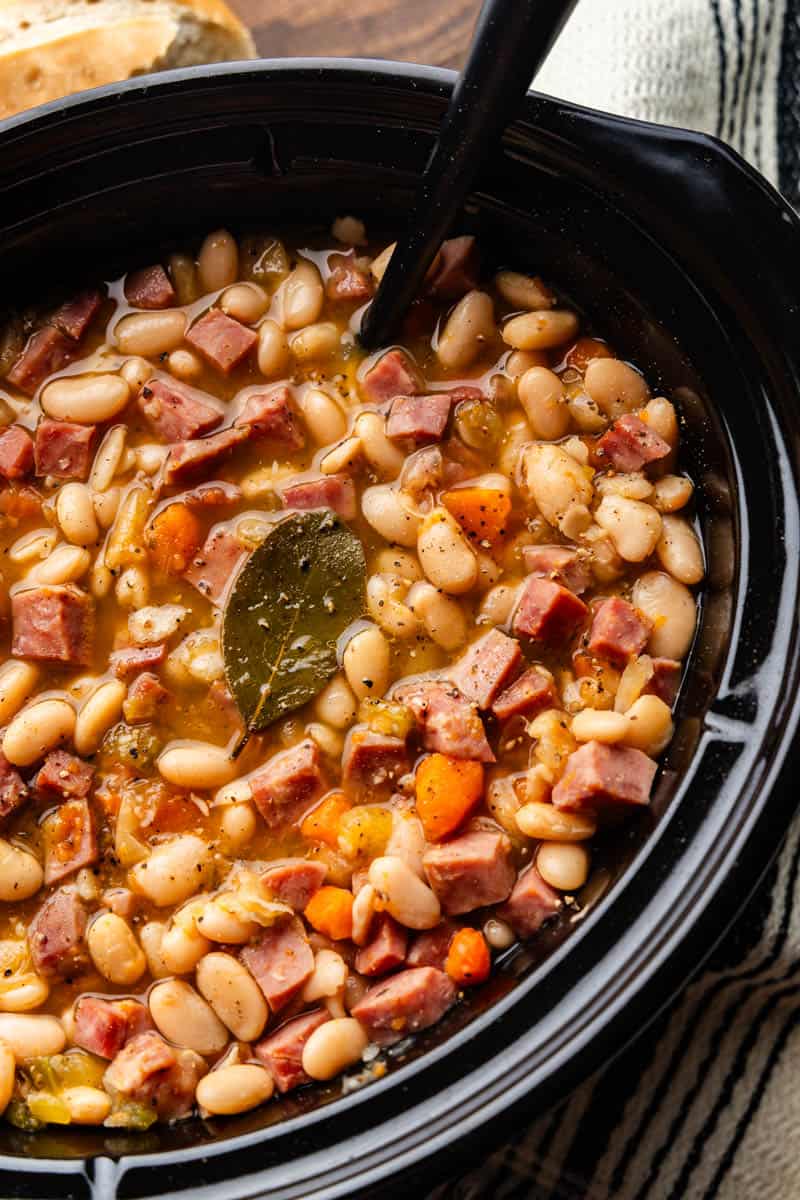 An overhead view of a slow cooker crock full of ham and beans.