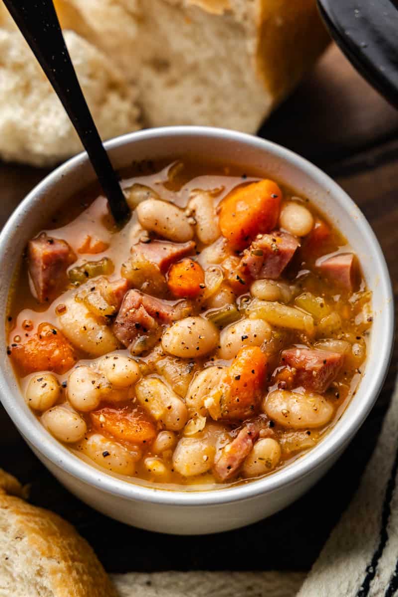 An overhead view of a white bowl filled with ham and beans made in the slow cooker.