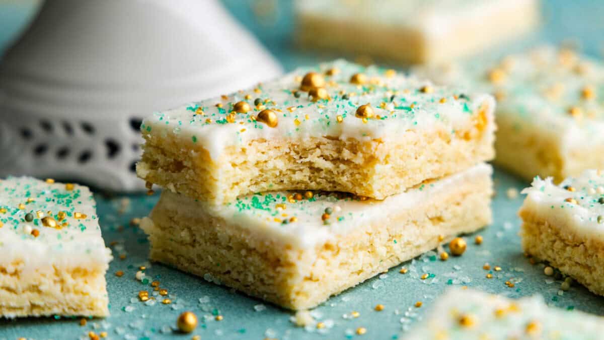 Two sugar cookie bars stacked on top of each other. The top one has a bite taken out of it.