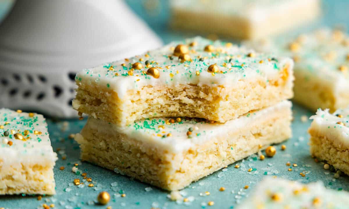 Two sugar cookie bars stacked on top of each other. The top one has a bite taken out of it.