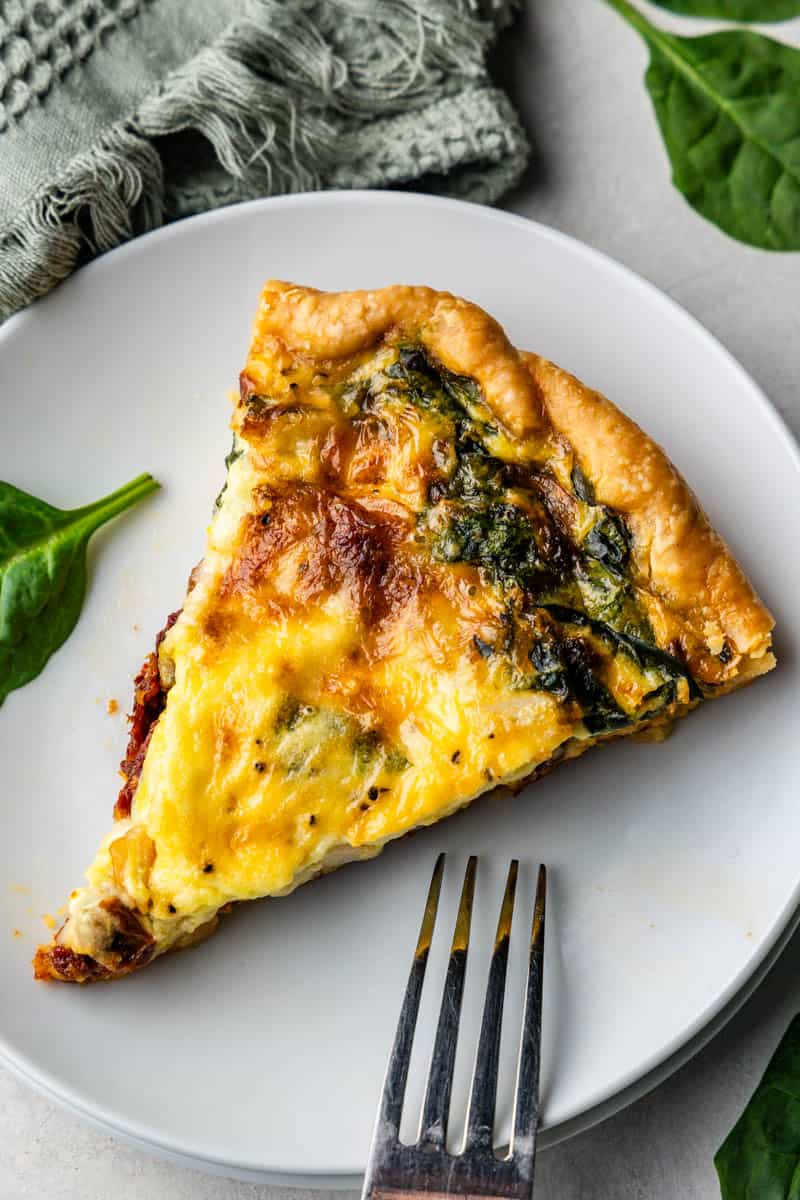 top view of slice of tuscan quiche on white plate with fork