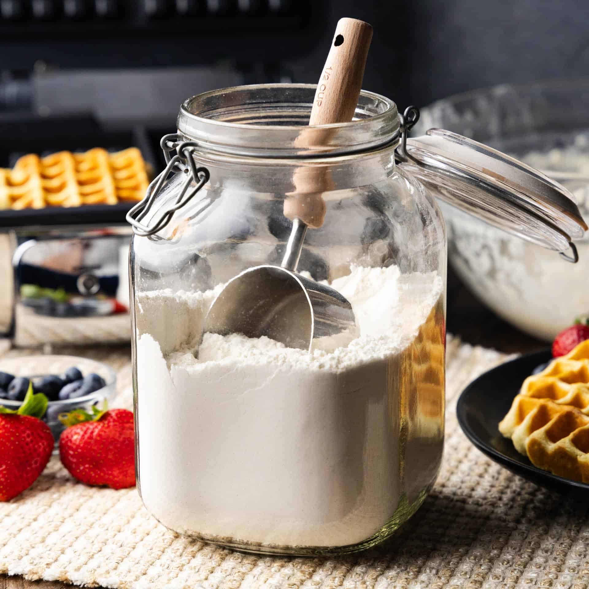 A large jar of homemade waffle mix with a measuring cup in it.