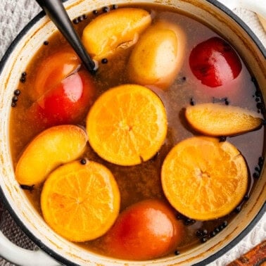 Wassail in large cooking pot, soaking fruit and spices, with a ladle inside.