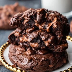 A stack of 3 ooey gooey chocolate chunk cookies on a golden plate.