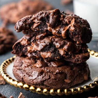 A horizontal image of a stack of 3 ooey gooey chocolate chunk cookies on a golden plate.