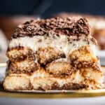 Straight on shot of tiramisu slice cut in half on a plate.