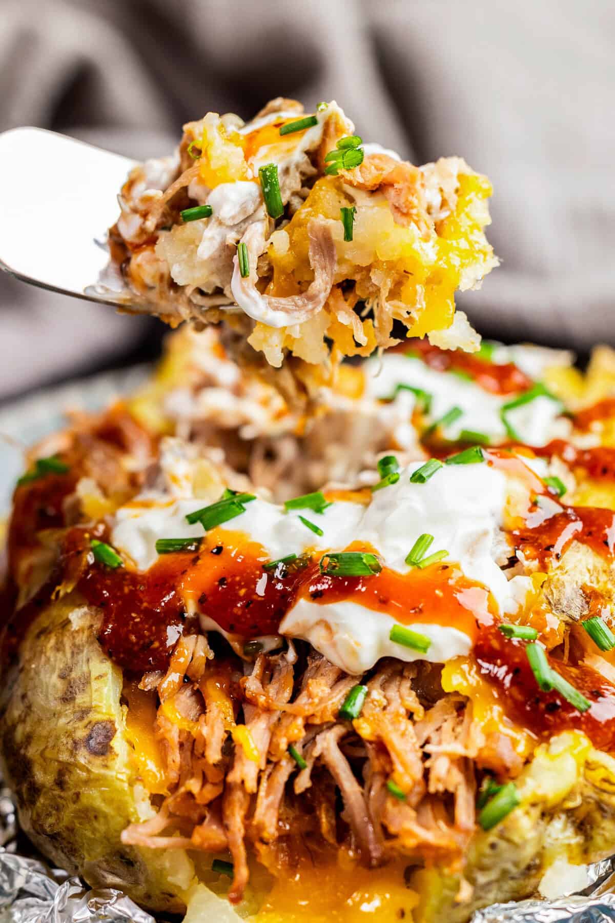 Closeup view of fork bite being pulled out of loaded pulled pork potato.