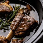 A close up view of a braised beef short rib in the crock of a slow cooker.