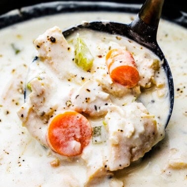 Creamy chicken soup in a ladle in a slow cooker.