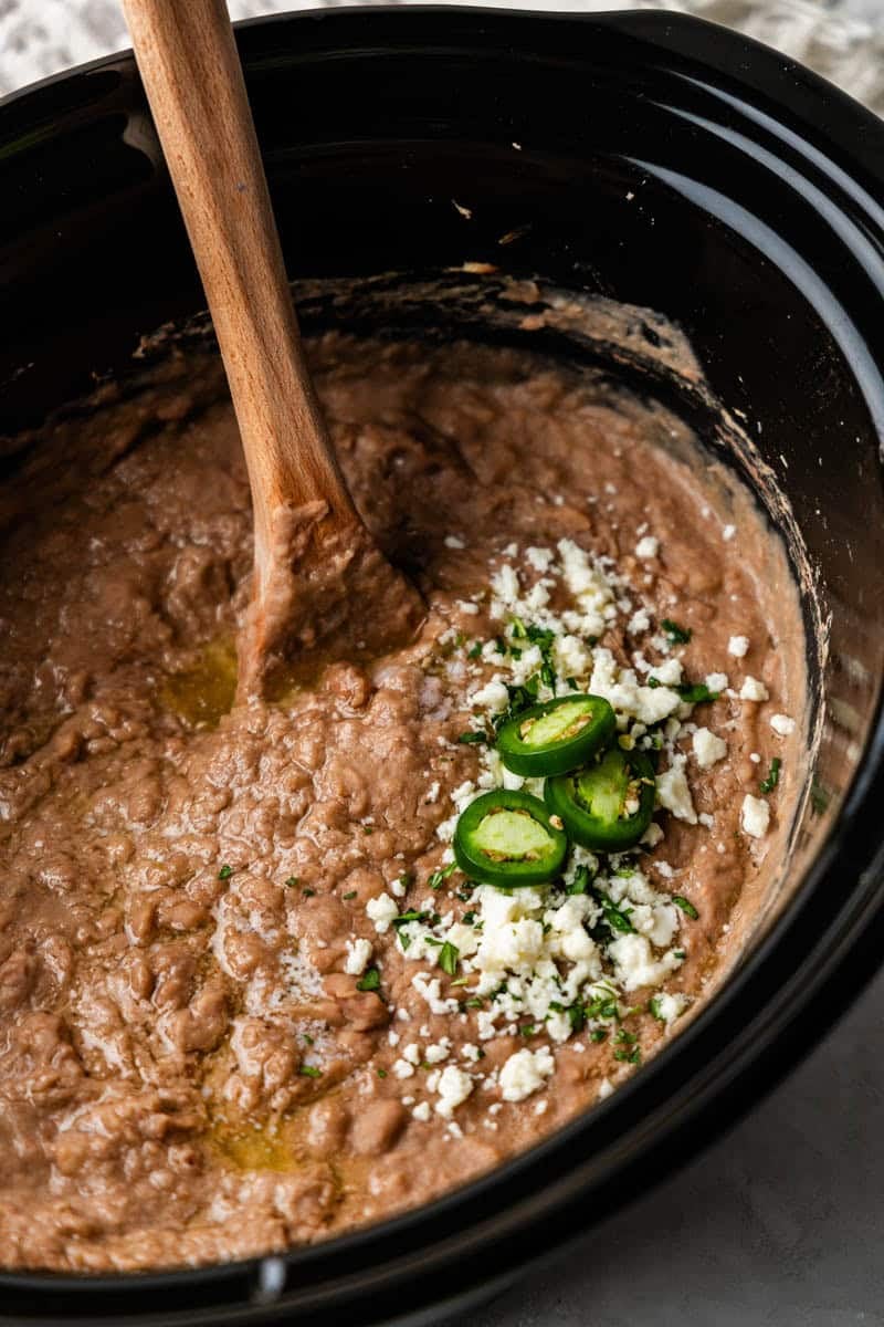 Angled shot of cooked pinto beans in slow cooker.