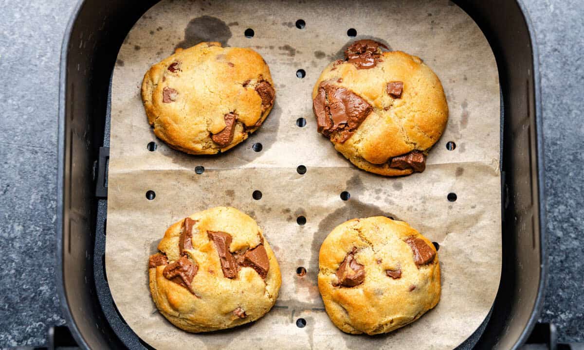 Chocolate chip cookies in air fryer basket.