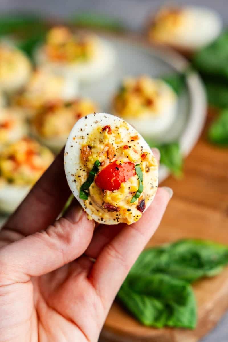 Hand holding a BLT Deviled Egg.