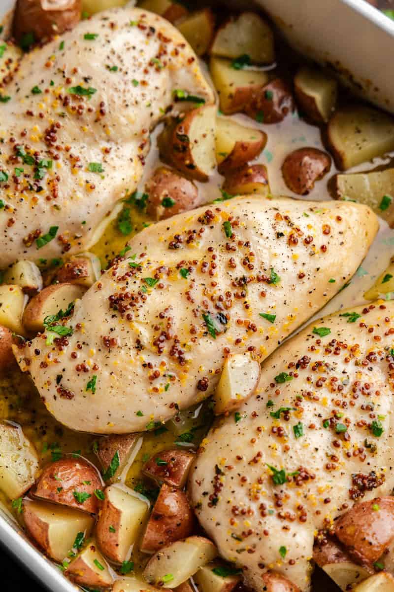 Closeup of Baked Honey Dijon Chicken and Potatoes in casserole dish.
