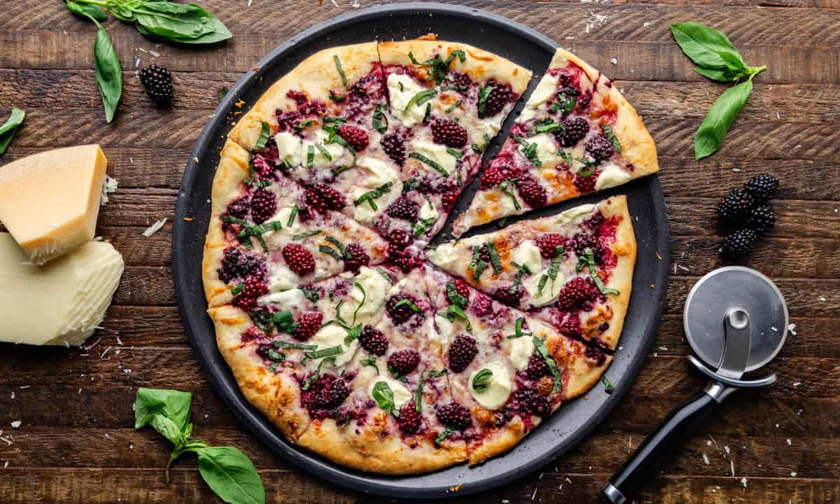 Overhead view of entire Blackberry Basil Ricotta Pizza sliced into pieces.