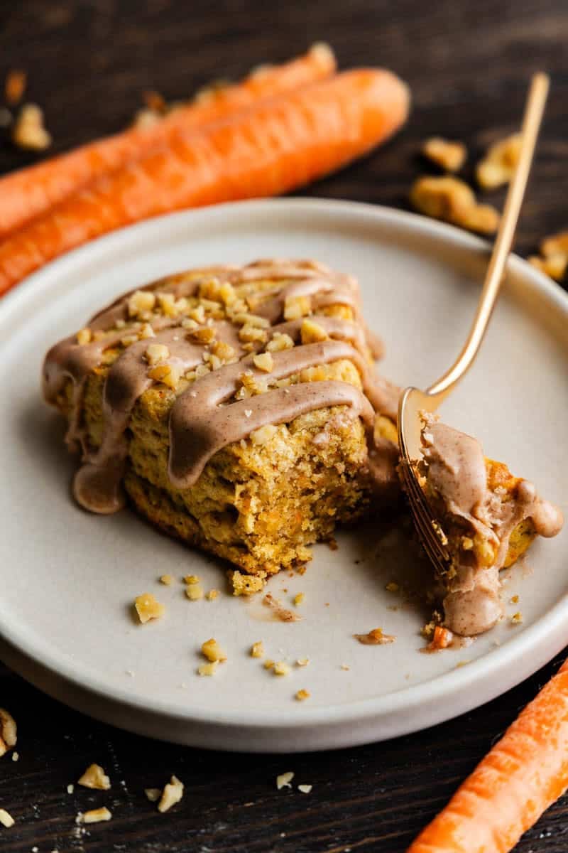 Fork taking a bite out of One Carrot Cake Scone on a white plate.