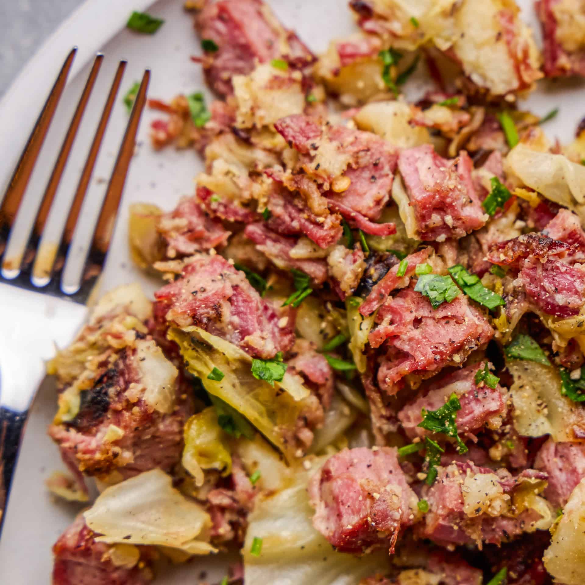 Closeup image of a plate full of corned beef and cabbage hash next to a fork.