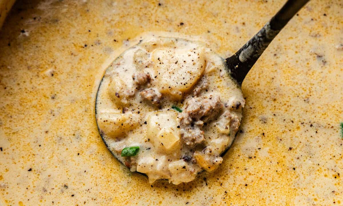 Closeup shot of Creamy Sausage Potato Soup in a ladle.