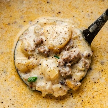 Closeup shot of Creamy Sausage Potato Soup in a ladle.