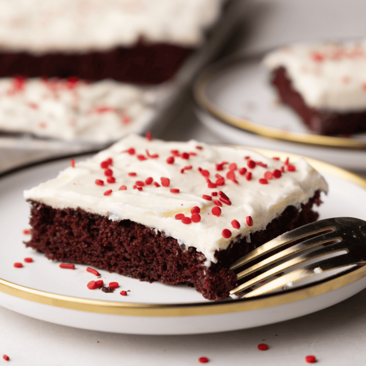 A close up view of a slice of red velvet sheet cake on a plate.