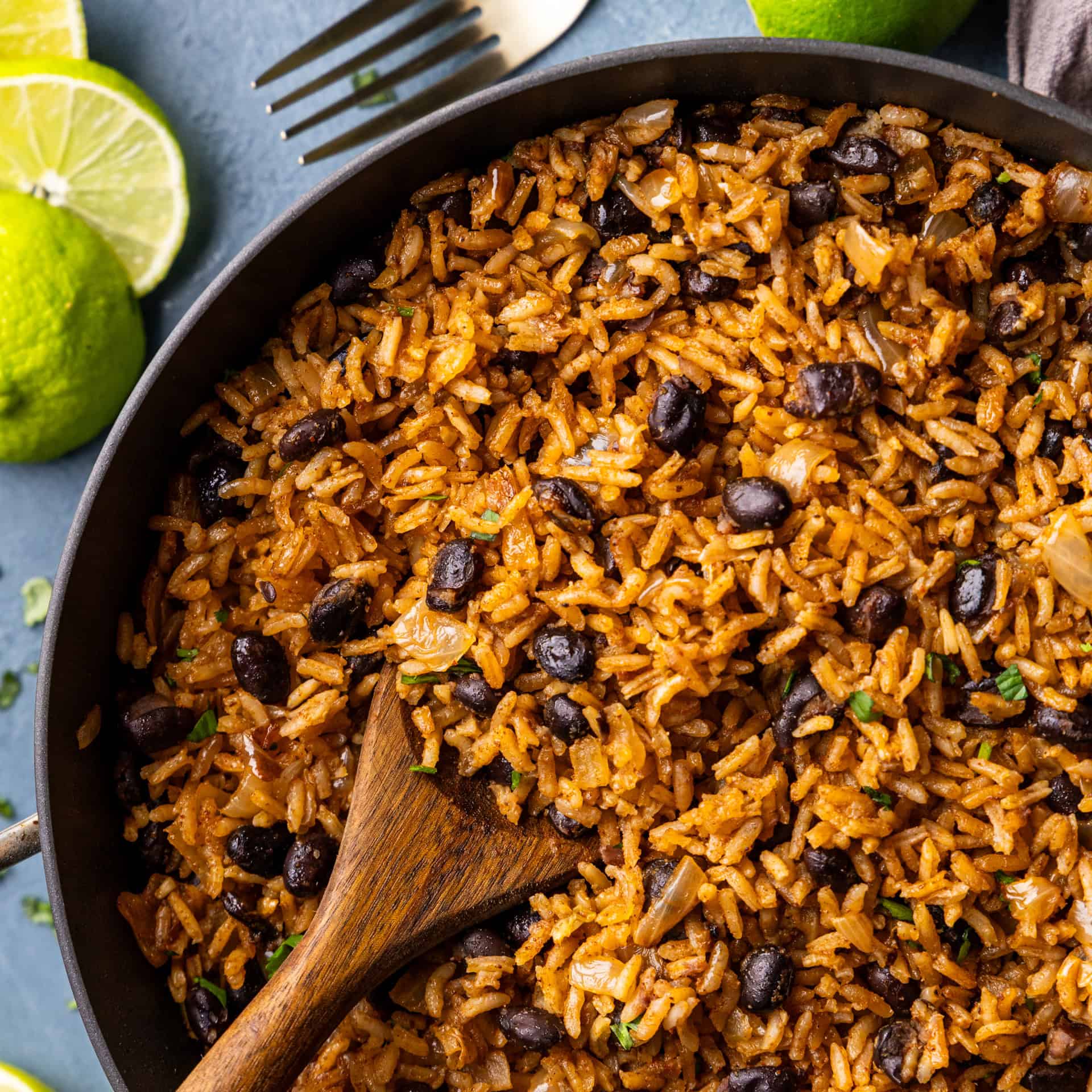 Wooden spoonful of Rice & Beans, Mexican, in a skillet.