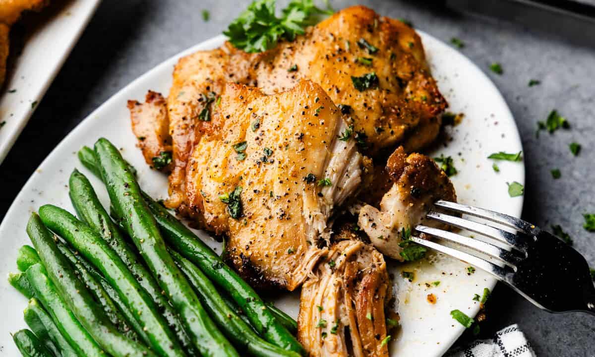 Sheet Pan Boneless Skinless Chicken Thighs piled on a plate with green beans.