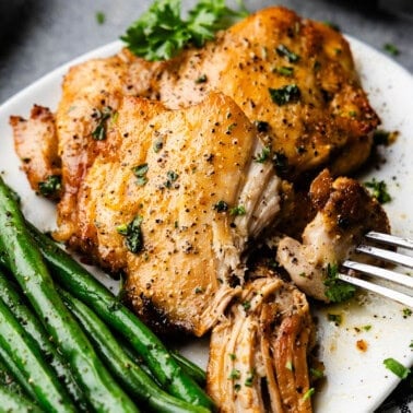 Sheet Pan Boneless Skinless Chicken Thighs piled on a plate with green beans.