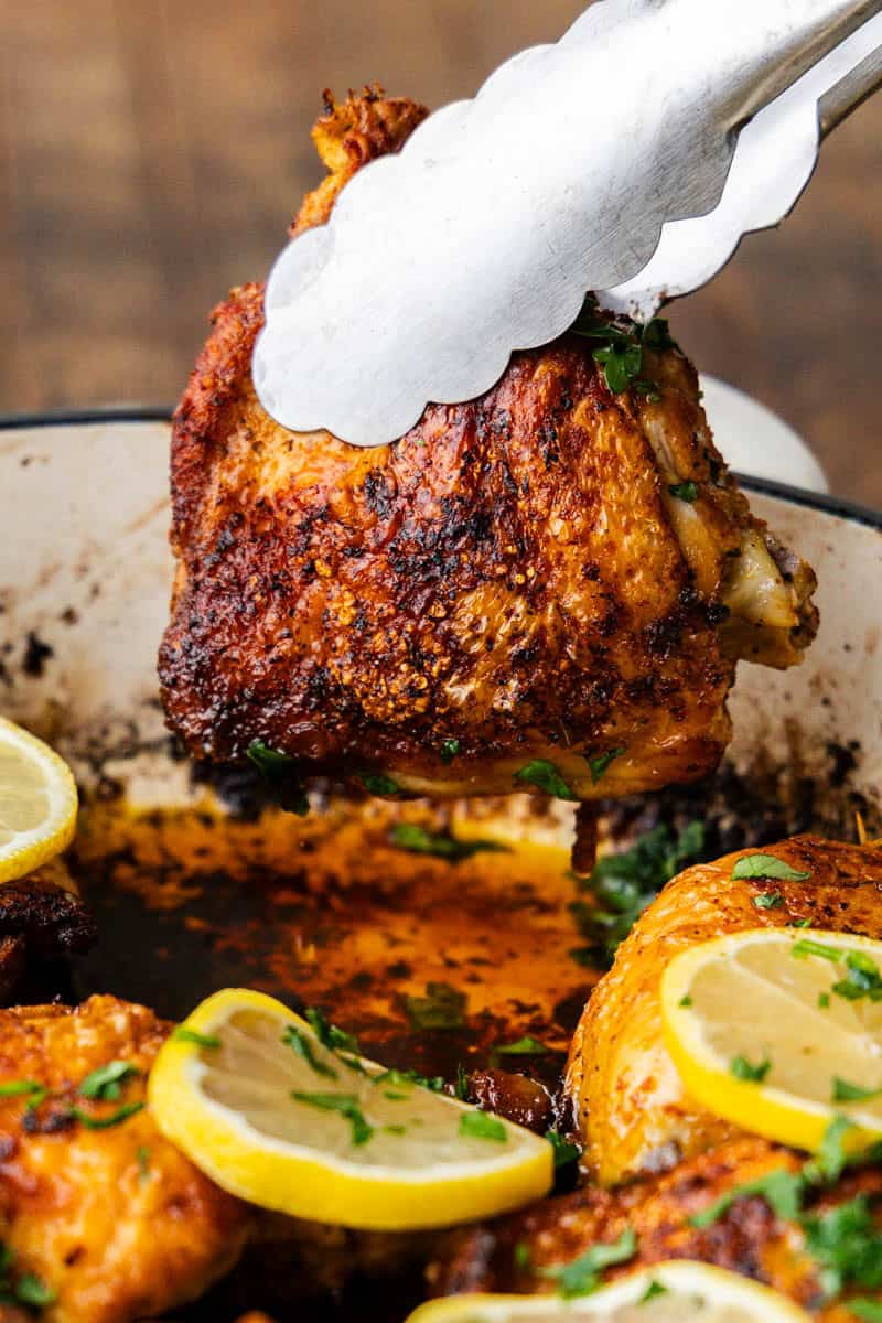 Tongs lifting Skillet Chicken Thighs.