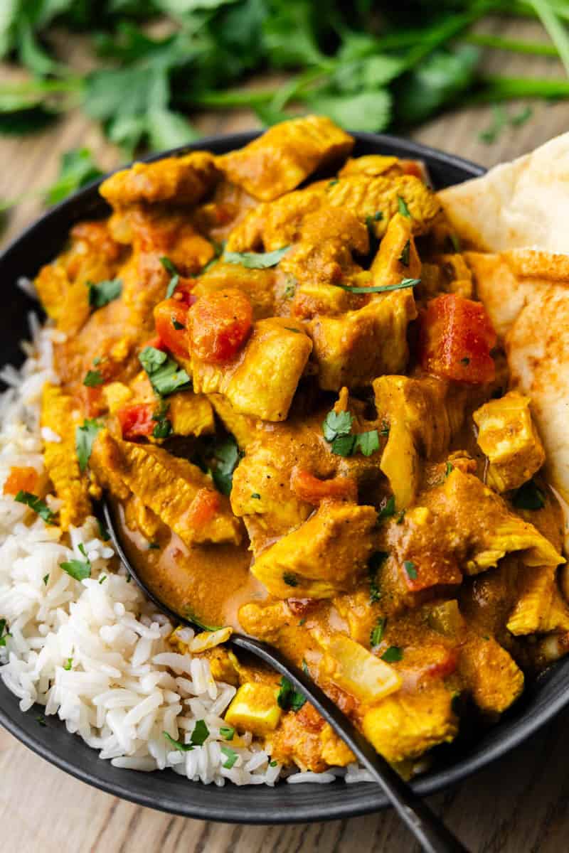 Slow Cooker Coconut Chicken Curry in a bowl with rice and spoon.