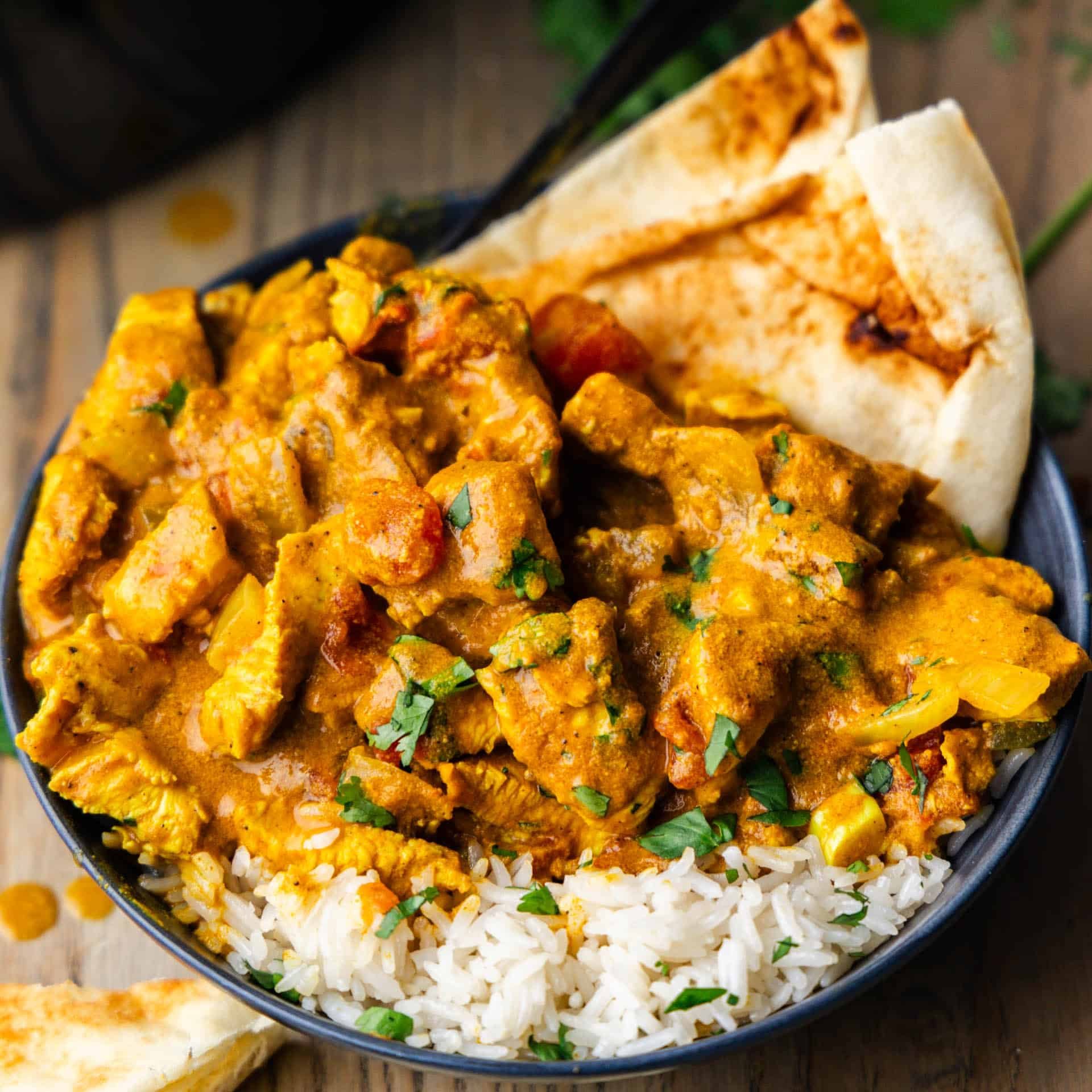 Slow Cooker Coconut Chicken Curry in a bowl with naan bread.