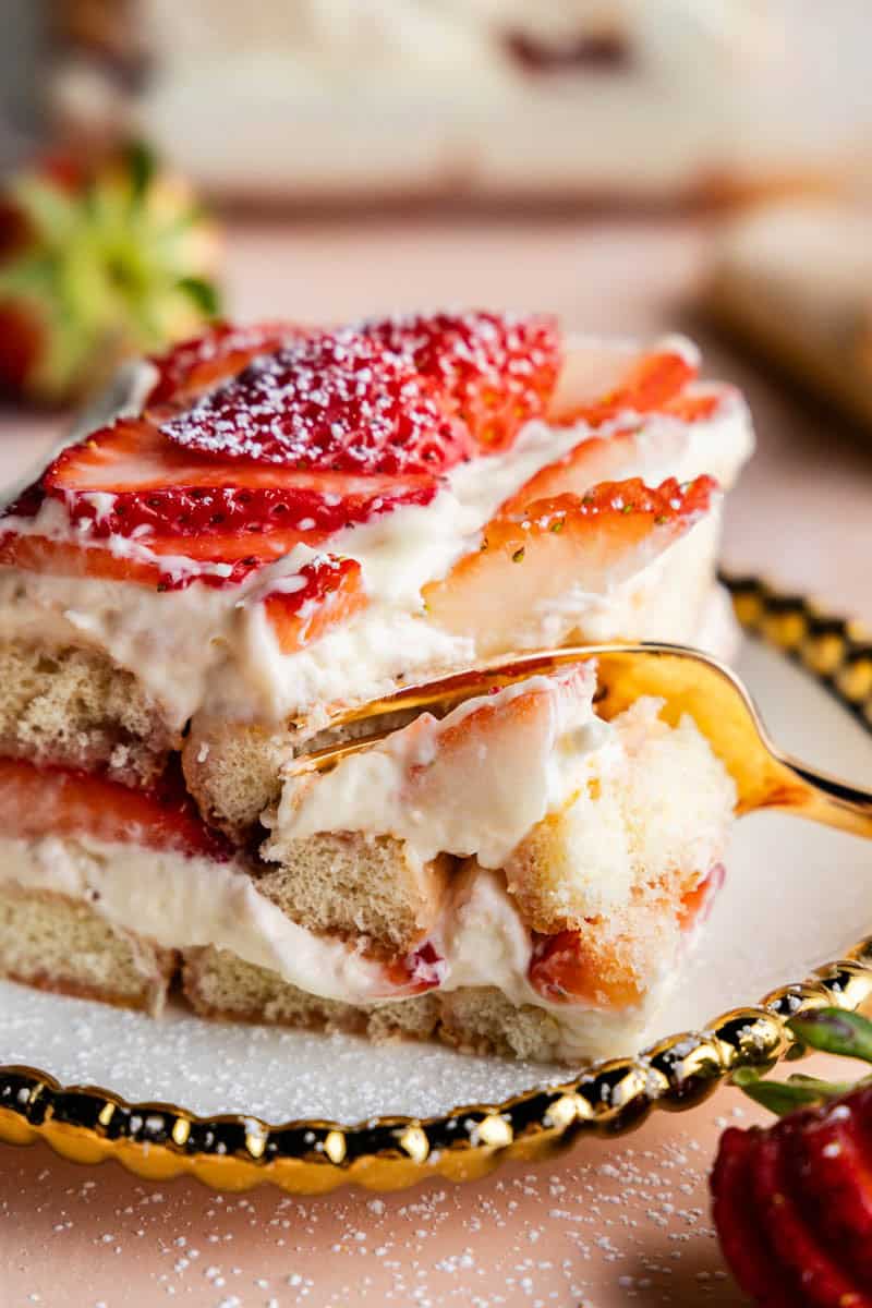 Slice of Strawberries & Cream Tiramisu on a plate with a bite taken out.