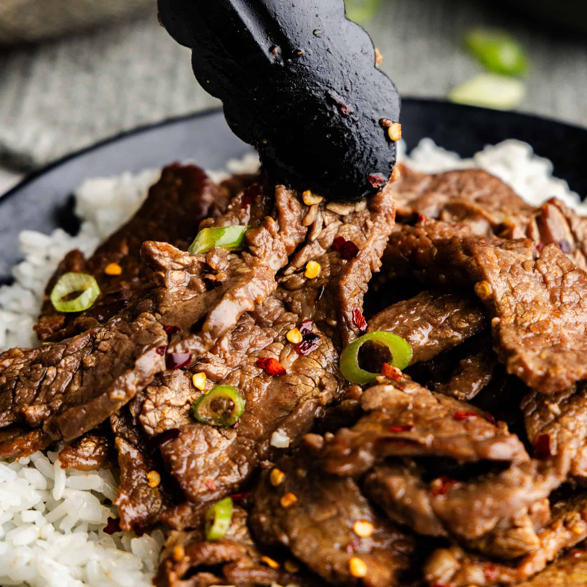 Closeup of 15-Minute Mongolian Beef being picked up by tongs.