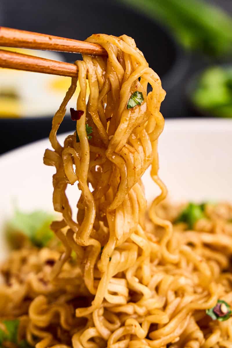 Closeup image of chopsticks holding 15 Minute Sriracha Ramen Noodles.