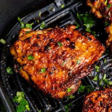 Closeup of chicken thighs in air fryer.