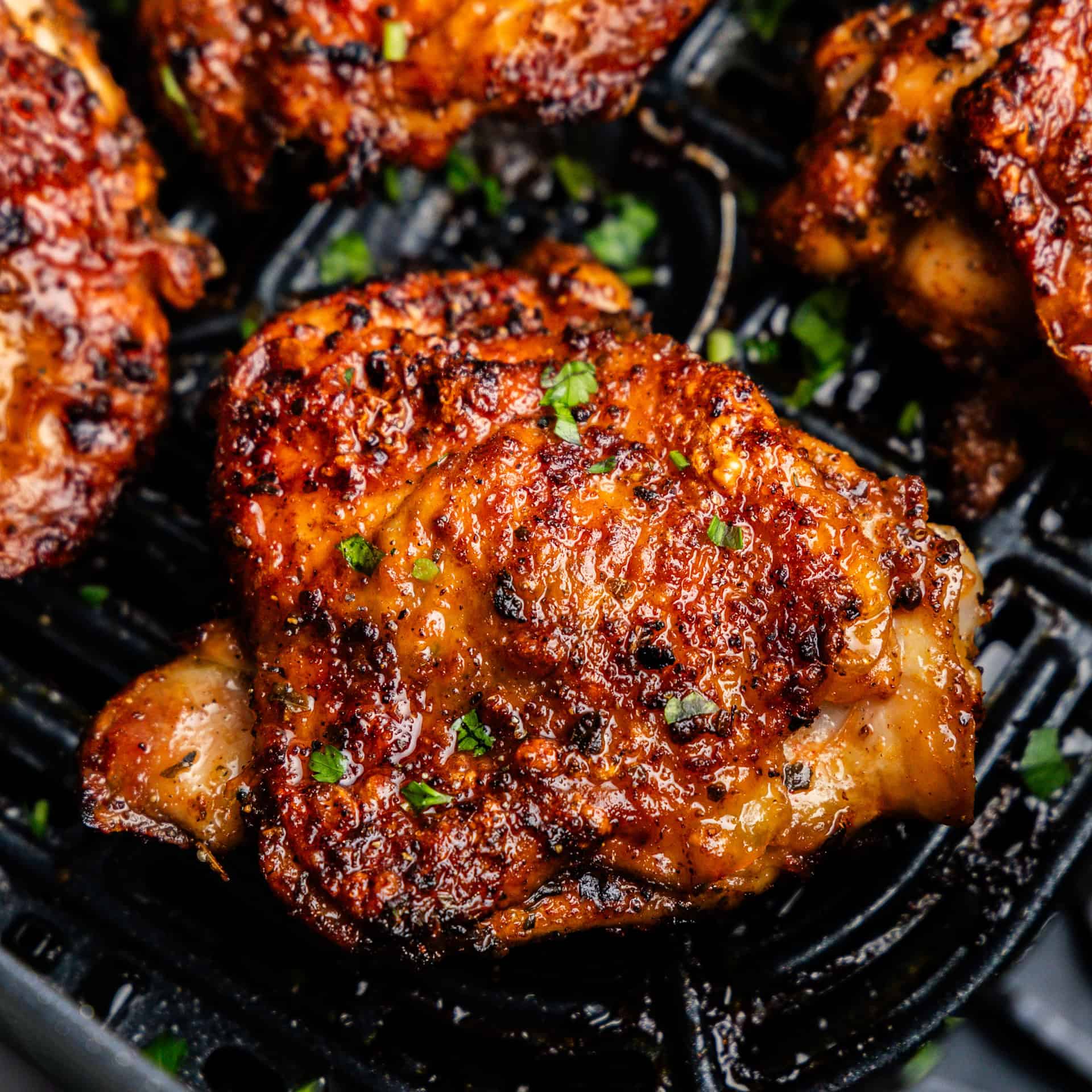 Closeup of chicken thighs in air fryer.