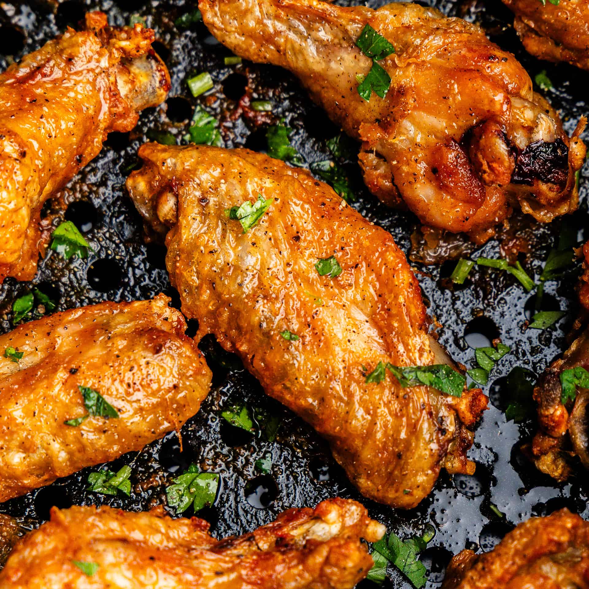 Closeup of chicken wings in air fryer.