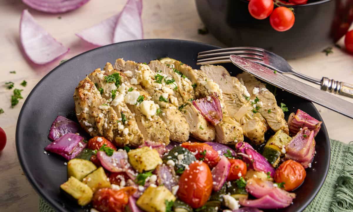 Air Fryer Greek Chicken & Veggies on a plate with ingredients surrounding.