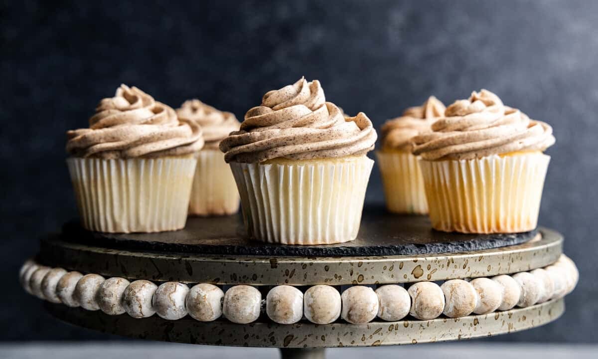 Five cupcakes frosted with browned butter frosting on a cake stand.