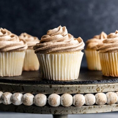 Five cupcakes frosted with browned butter frosting on a cake stand.