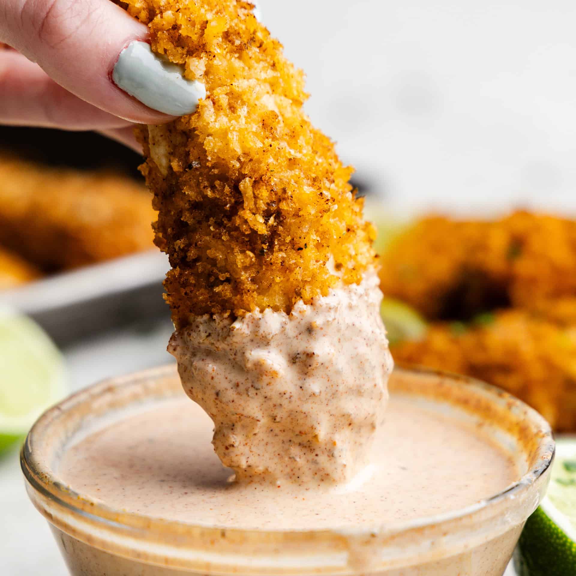 Chili-Lime Baked Chicken Tender being dipped into the sauce.