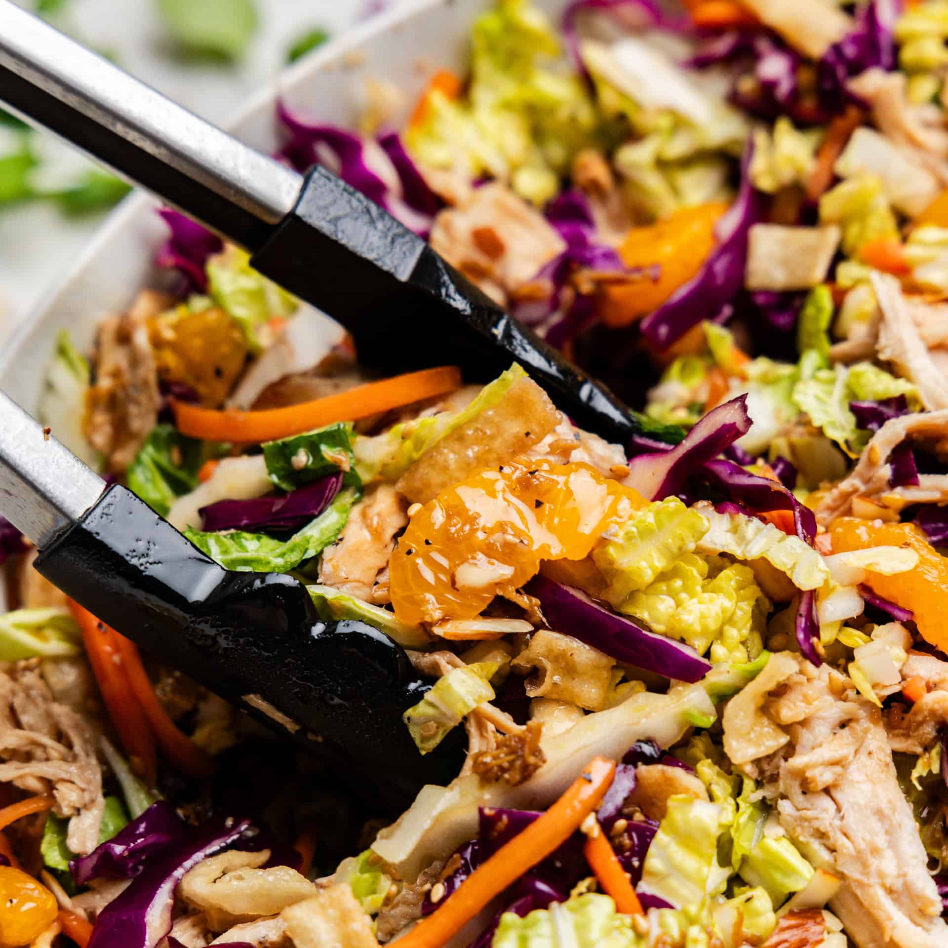 Closeup of Chinese Chicken Salad getting picked up by tongs.