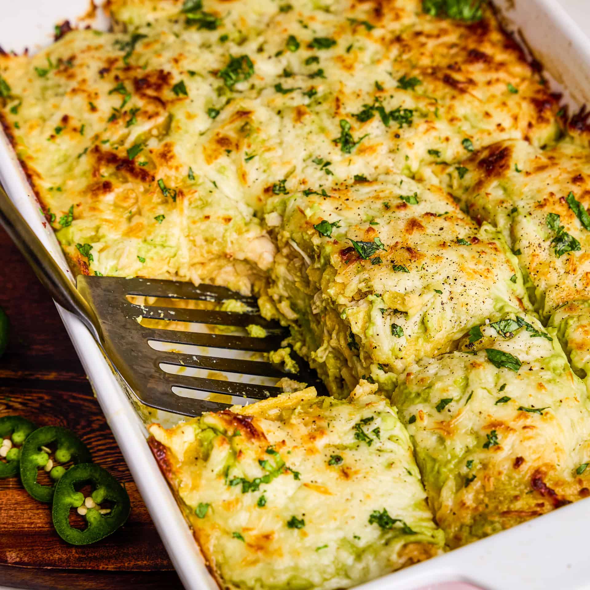 Creamy Chicken Enchilada Casserole being dished out with a spatula.