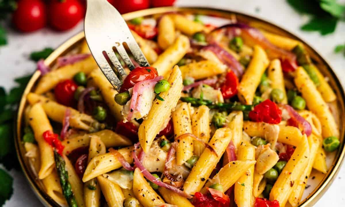 Closeup of Creamy Pasta Primavera on a plate with a fork bite.