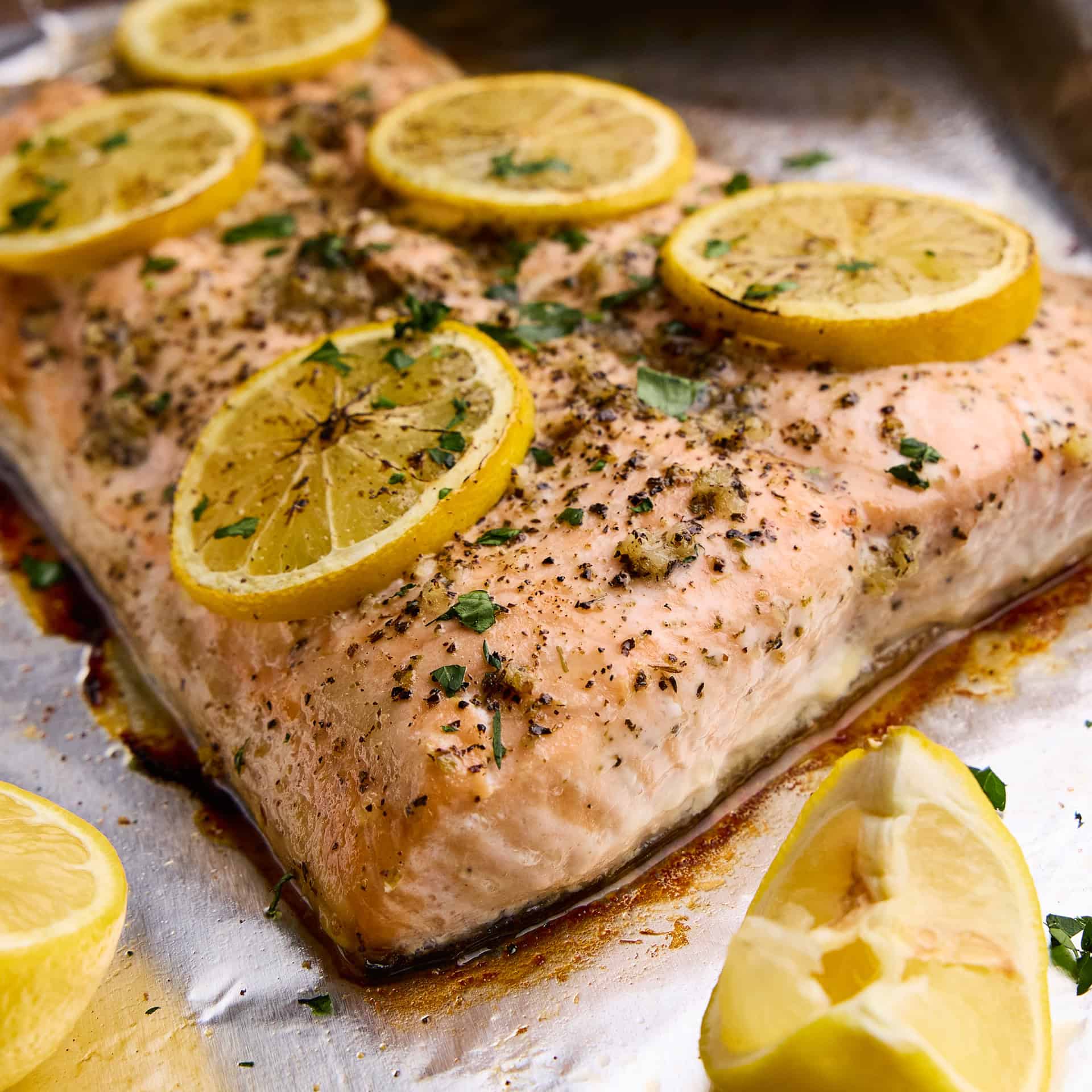 Easy Garlic Herb Baked Salmon topped with lemons on a sheet pan.