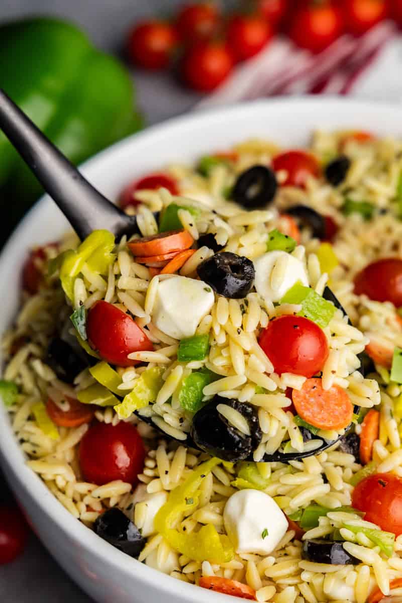 La ensalada de pasta orzo italiana recogió una cuchara para servir.